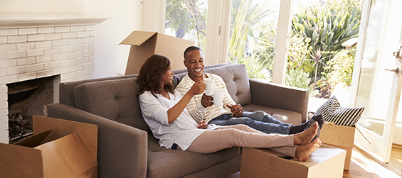 Couple sits on couch surround by moving boxes